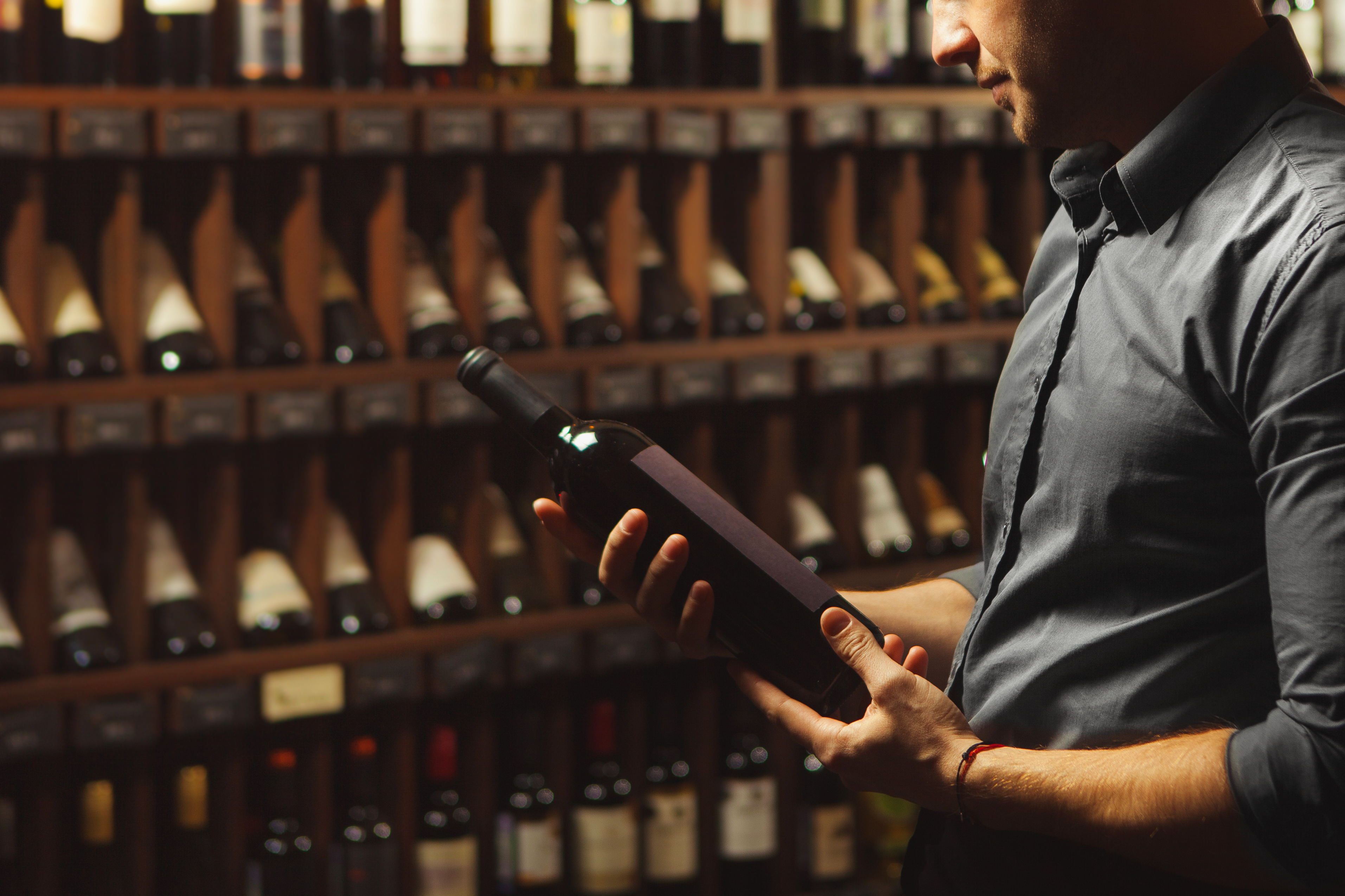 close-up-portrait-sommelier-holding-wine-bottle-wine-cellar-background.jpg